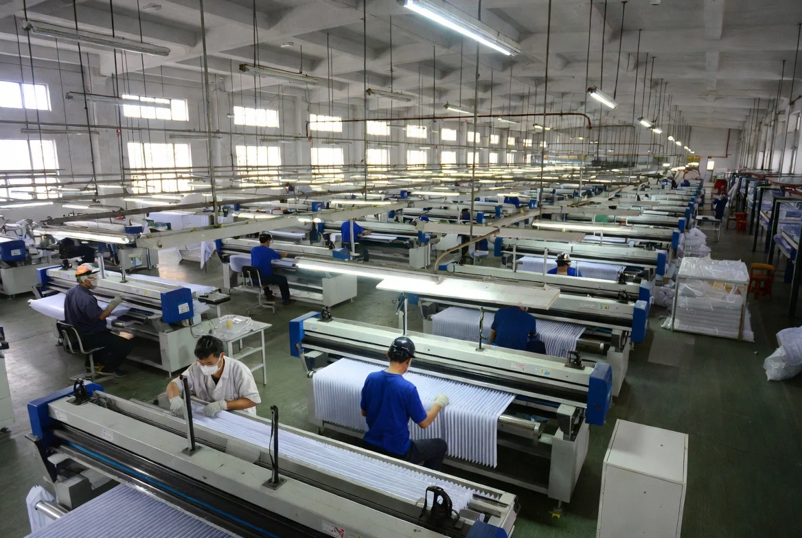 Long rows of pleating and inspection machines on the CAIC factory floor